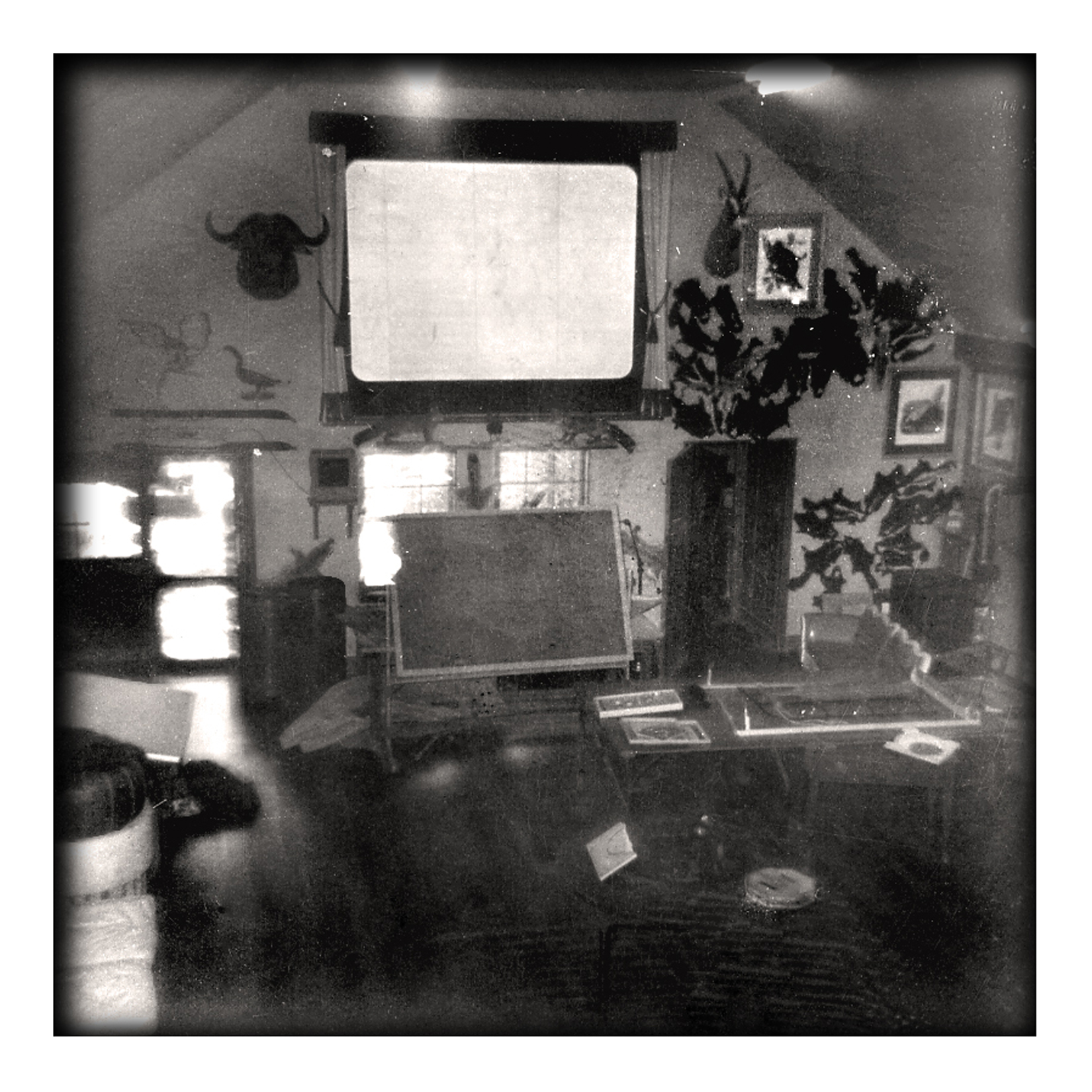 The Lodge's movie theater in 1953, projection screen above a stone mantel with mounted game, framed prints, and a drafting easel below