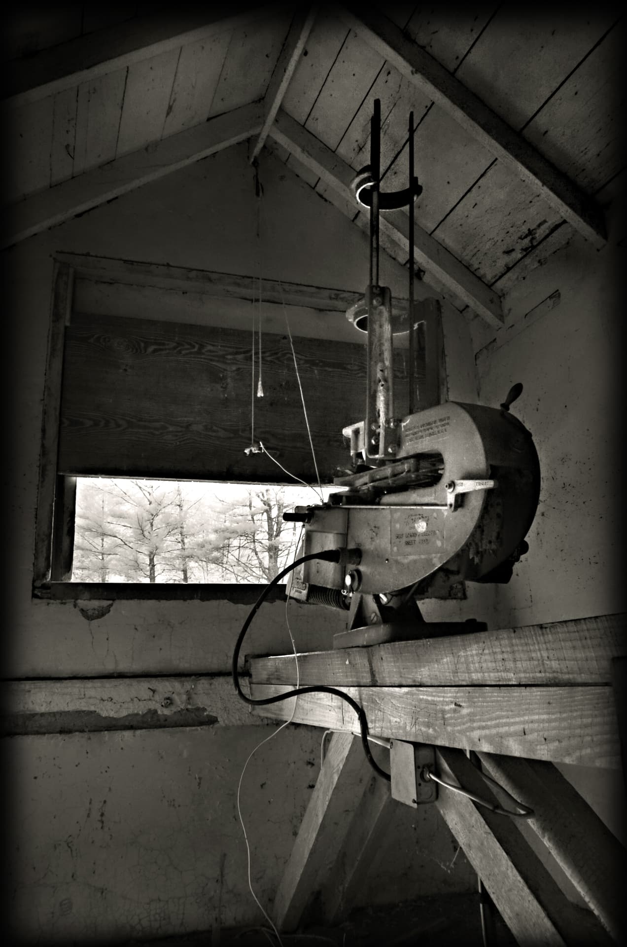 Black and white photograph inside a skeet house at Devotion showing the original self-loading target thrower mounted on a timber frame beside the throwing window