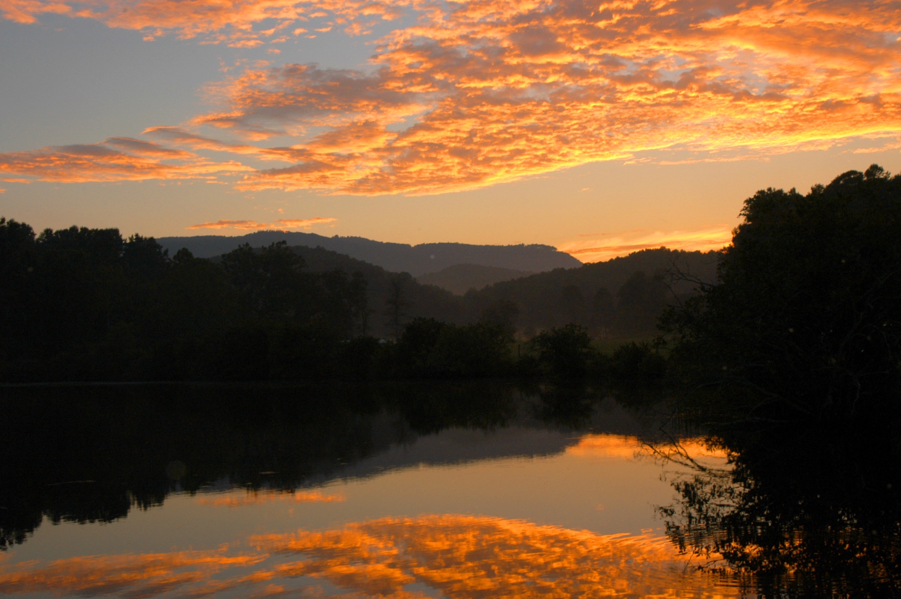 Sunset over the mountains reflected in a still lake at Devotion