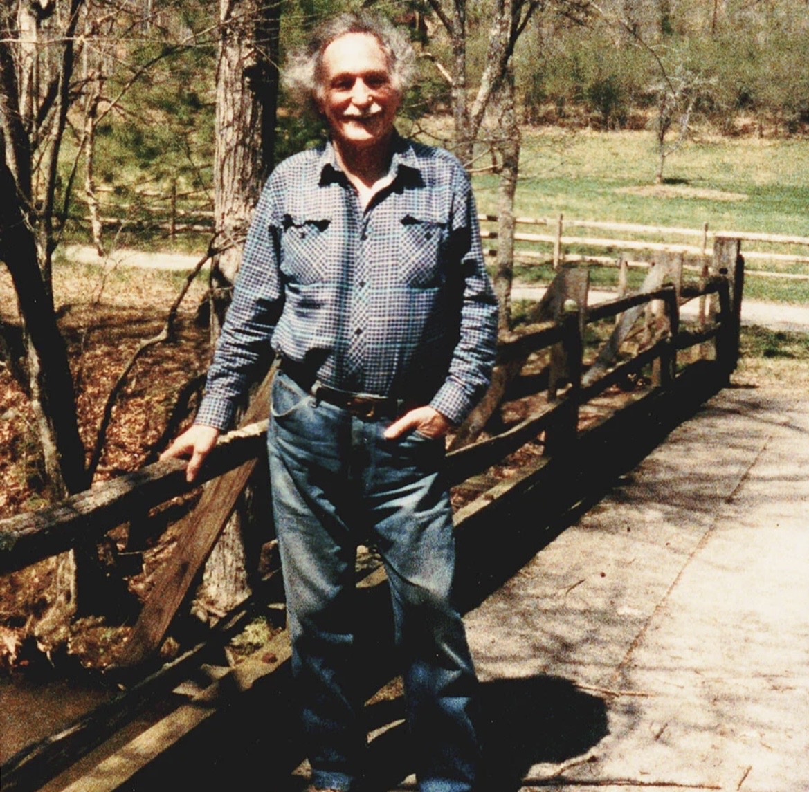 Andrija Puharich standing on a plank bridge over a forest stream at Devotion