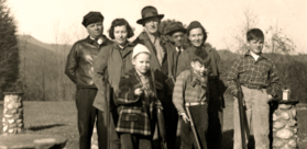 Black and white photograph of Zach and Will Reynolds with Blitz Reynolds and friends standing together at the stone Skeet House at Devotion